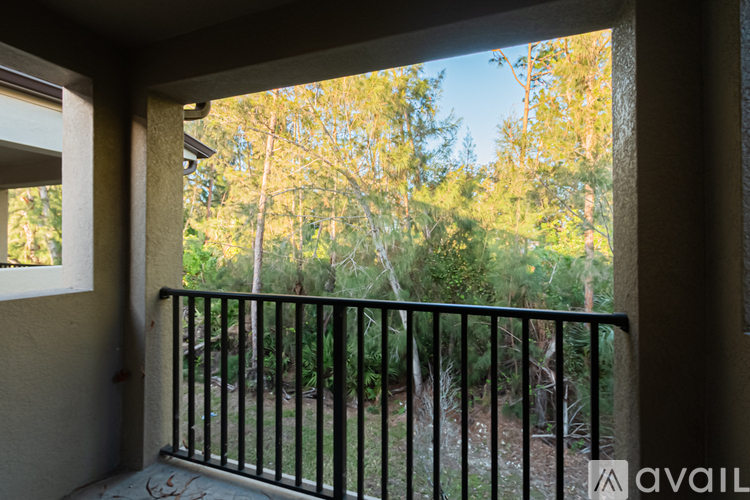 A balcony with a black railing overlooking a green yard.