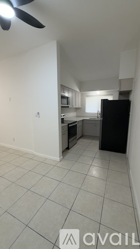 A kitchen with a black refrigerator and white cabinets.