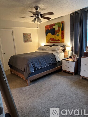 A bedroom with a bed, nightstand, and a painting on the wall.