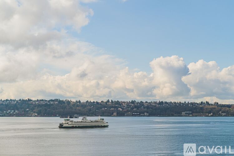 A ferry is sailing on a calm body of water with a cloudy sky above.