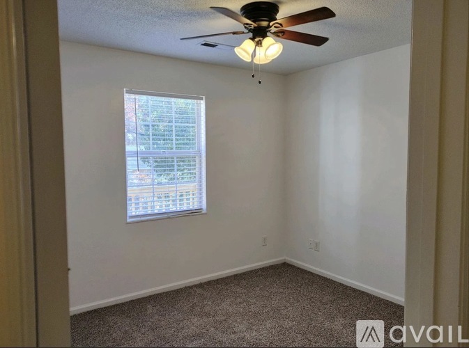 A room with a ceiling fan and a window with blinds.