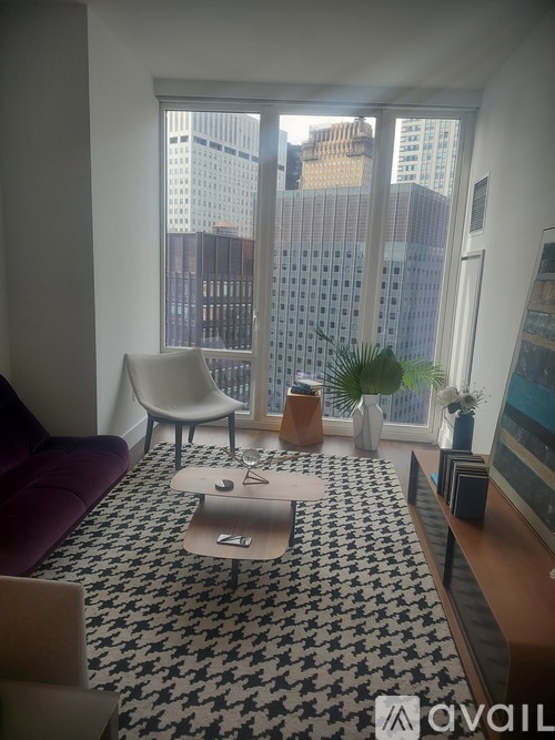 A living room with a purple couch and a black and white patterned rug.