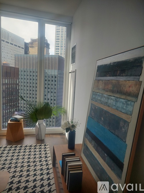 A room with a large window overlooking a cityscape and a large abstract painting on the wall.