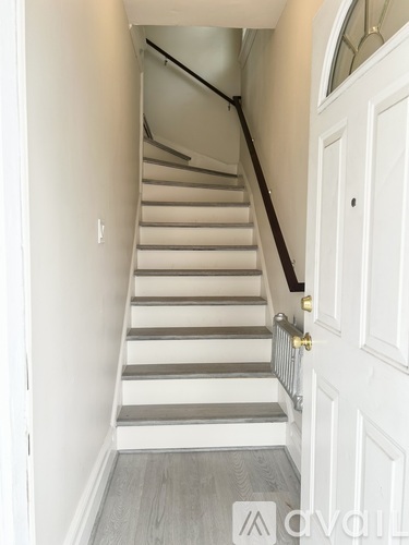 A white door is on the right and a staircase is on the left.
