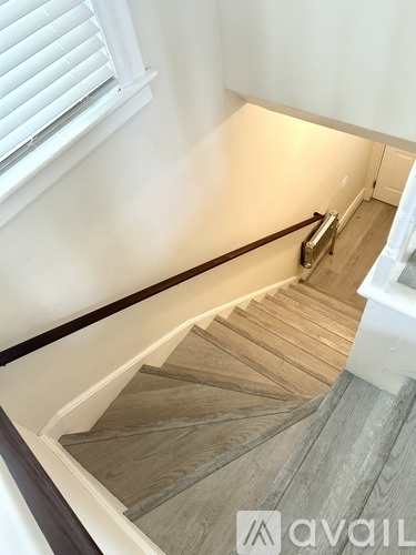A staircase with wooden steps and a white wall.