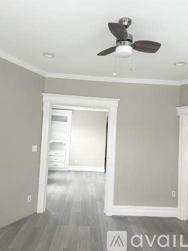A room with a ceiling fan and a doorway leading to another room.