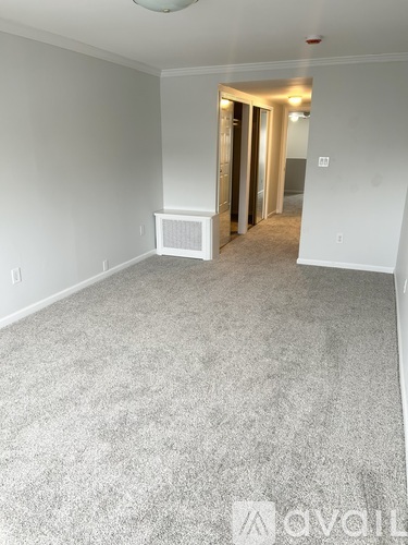 A spacious room with a carpeted floor and white walls.