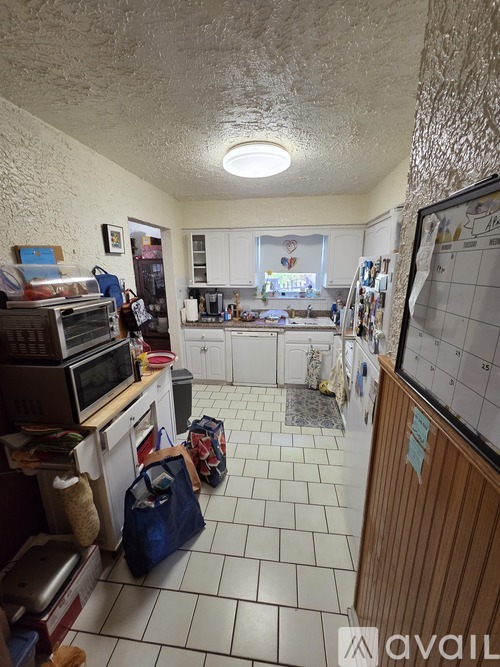 A kitchen with a white tile floor and a calendar on the wall.
