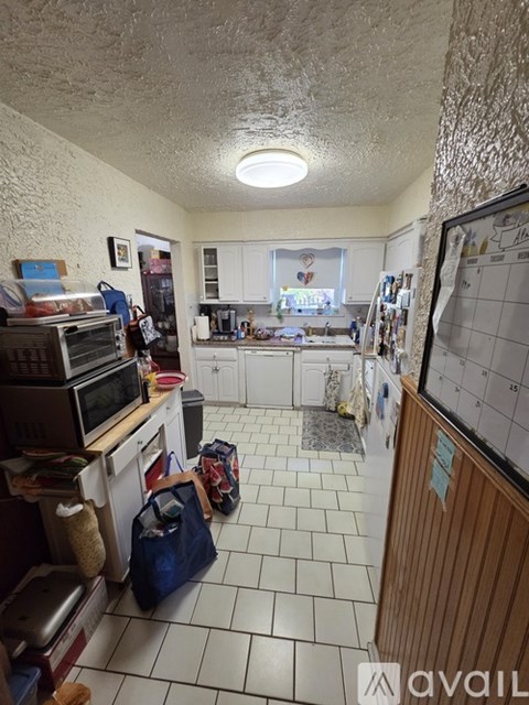 A kitchen with a white tile floor and a calendar on the wall.