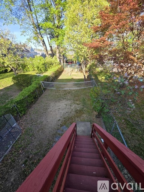 A red staircase leads down to a grassy area with trees.