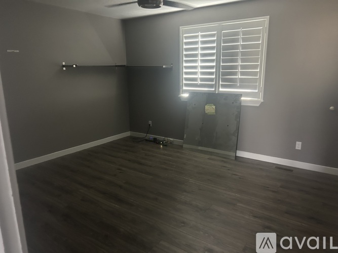 A room with wooden flooring and a window with blinds.