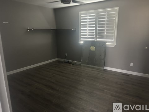 A room with wooden flooring and a window with blinds.