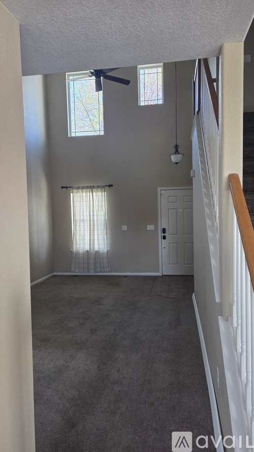 A room with a carpeted floor and a ceiling fan.