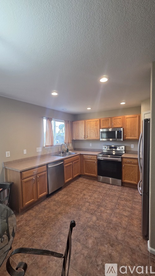 A kitchen with brown cabinets and a black chair.