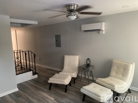 A living room with two white chairs and a small table.
