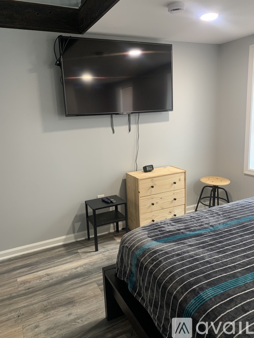 A bedroom with a bed, nightstand, and a television mounted on the wall.