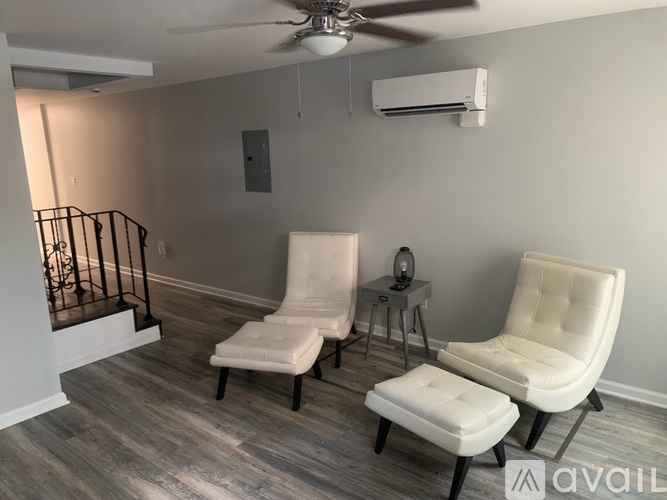 Two white leather chairs and a table are in a room with a ceiling fan.