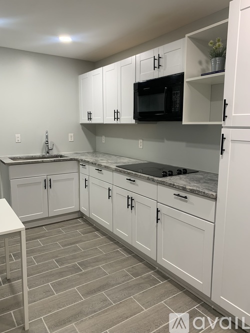 A kitchen with white cabinets and a black microwave.