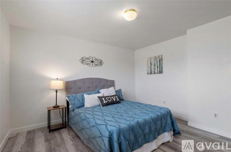 A bedroom with a blue bedspread and a lamp on a side table.