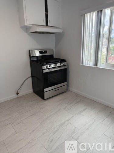 A black stove in a kitchen with a white wall and a window.