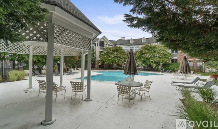 A pool area with a table and chairs under a pergola.