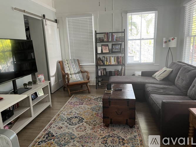A living room with a grey couch, a wooden coffee table, a chair, and a bookshelf.