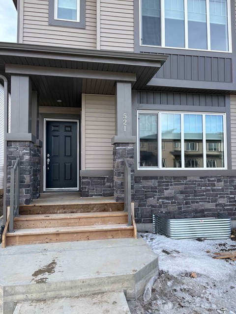 A grey house with a black door and a window with a number 521 on it.