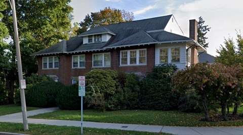 A red brick house with a black roof and white trim.