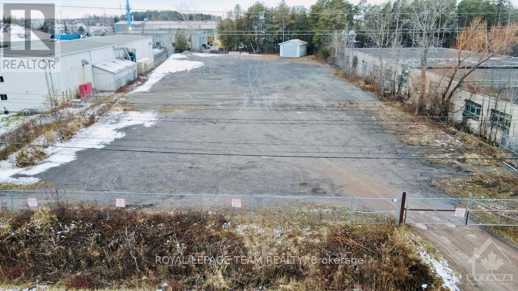 A large, empty parking lot with a fence and some buildings in the background.