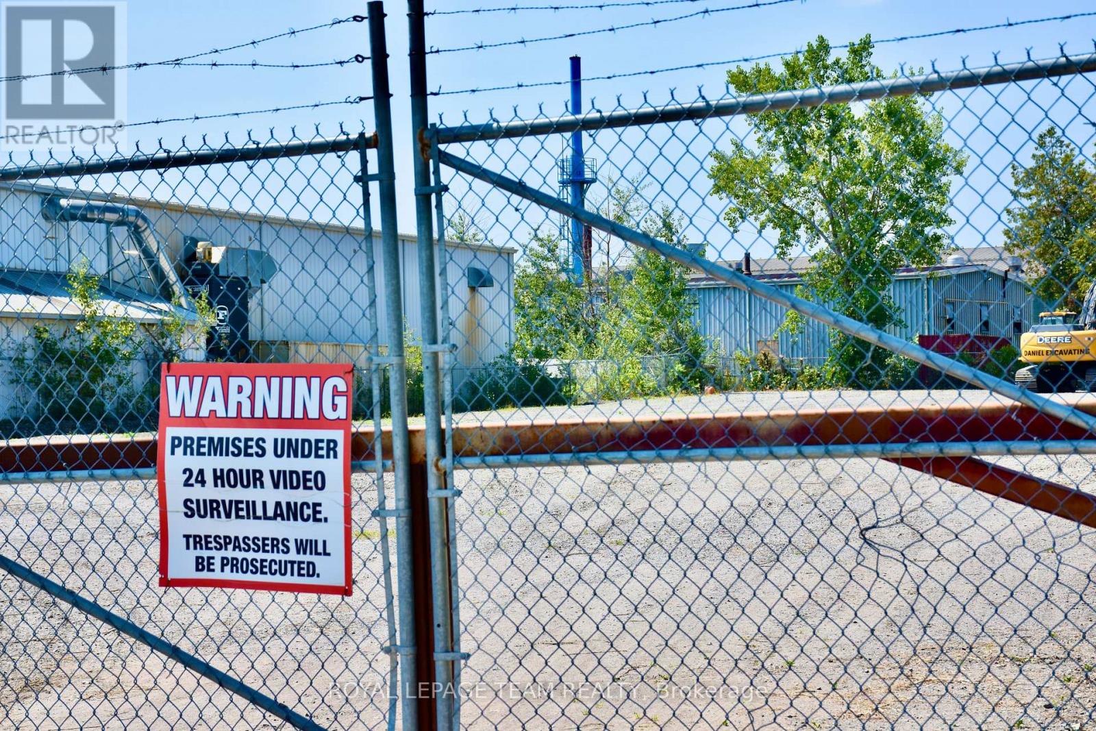 A sign on a fence warns that the premises are under 24 hour video surveillance and trespassers will be prosecuted.