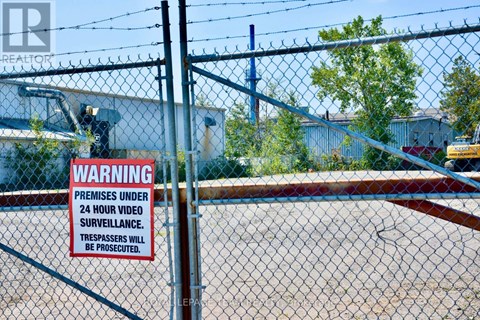 A sign on a fence warns that the premises are under 24 hour video surveillance and trespassers will be prosecuted.