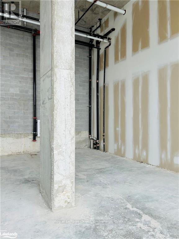A room under construction with exposed pipes and concrete pillars.