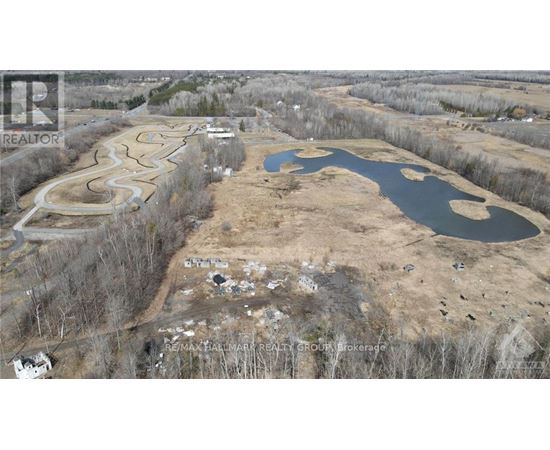 An aerial view of a real estate development with a pond and a winding road.