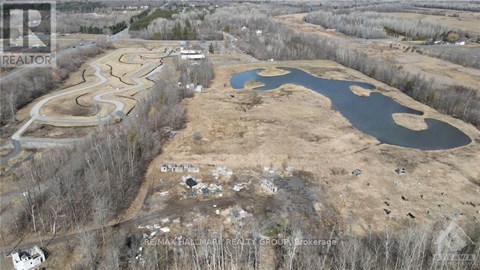 An aerial view of a real estate development with a pond and a winding road.