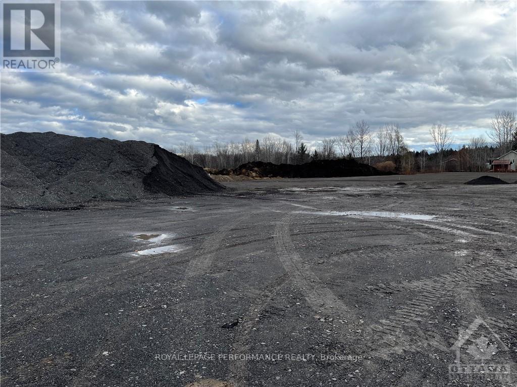 A large open area with tire tracks in the foreground and a pile of dirt in the background.