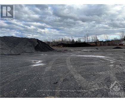 A large open area with tire tracks in the foreground and a pile of dirt in the background.