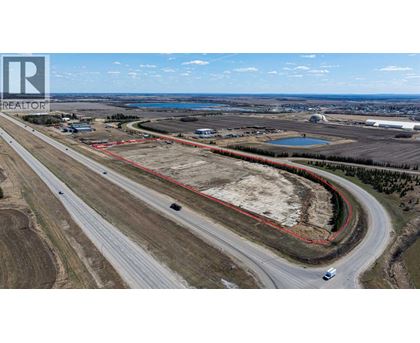 A realtor logo is visible on an aerial image of a road and surrounding land.