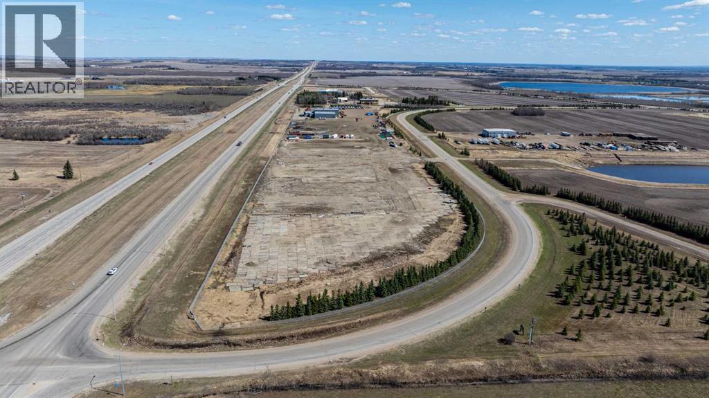 A highway with a curve leading to a small town with a lake in the distance.