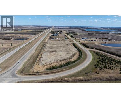 A highway with a curve leading to a small town with a lake in the distance.