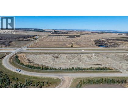A large open field with a road curving around it and a car driving on the road.