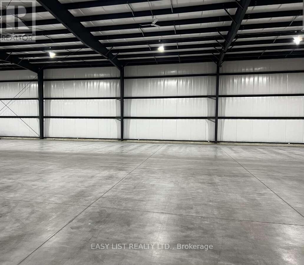A large, empty warehouse with a concrete floor and white walls.