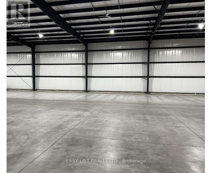 A large, empty warehouse with a concrete floor and white walls.