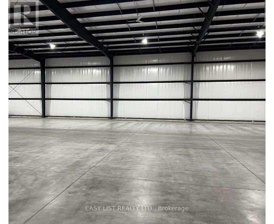 A large, empty warehouse with a concrete floor and white walls.