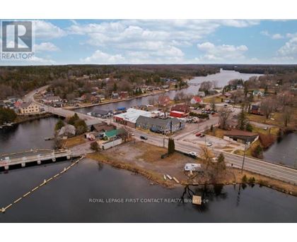 A real estate company logo is superimposed on an aerial view of a small town by a lake.