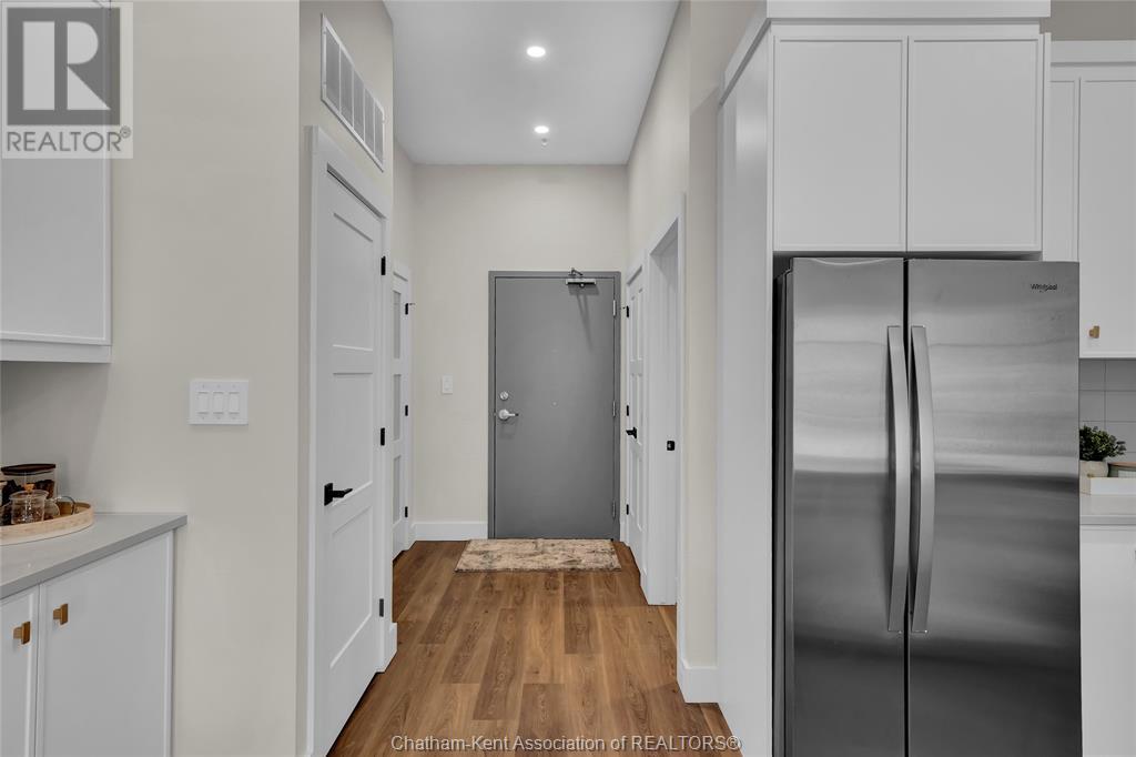 A kitchen with white cabinets and a stainless steel refrigerator.