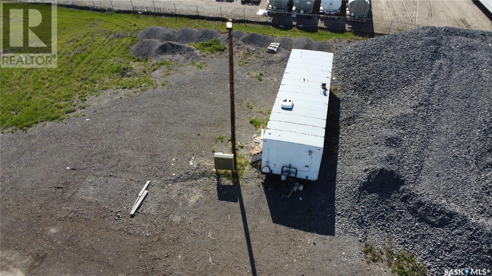 A white box truck is parked in a gravel lot.