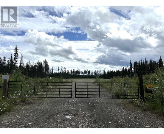 A gate with a sign that says REALTOR in front of a forest.