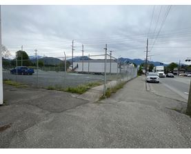 A view of a road with a blue car and a white car parked on the side.
