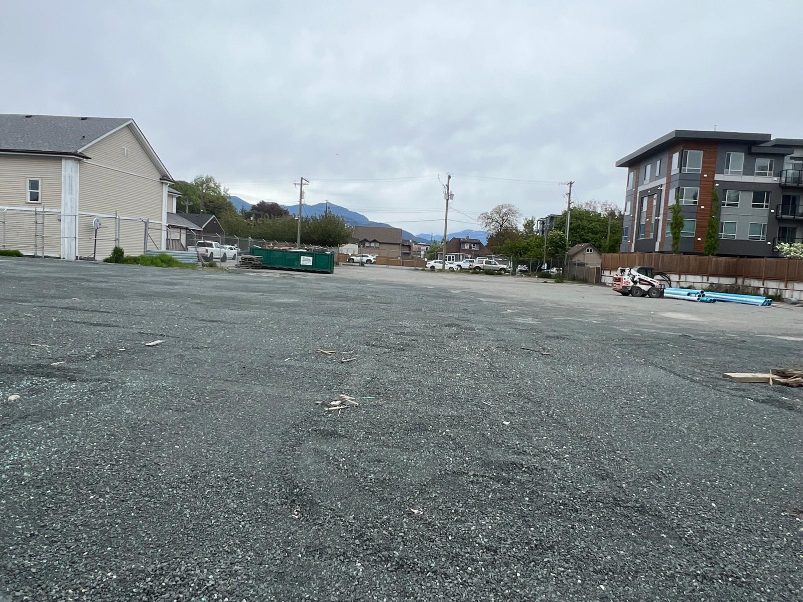 A parking lot with a few cars and buildings in the background.