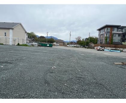 A parking lot with a few cars and buildings in the background.